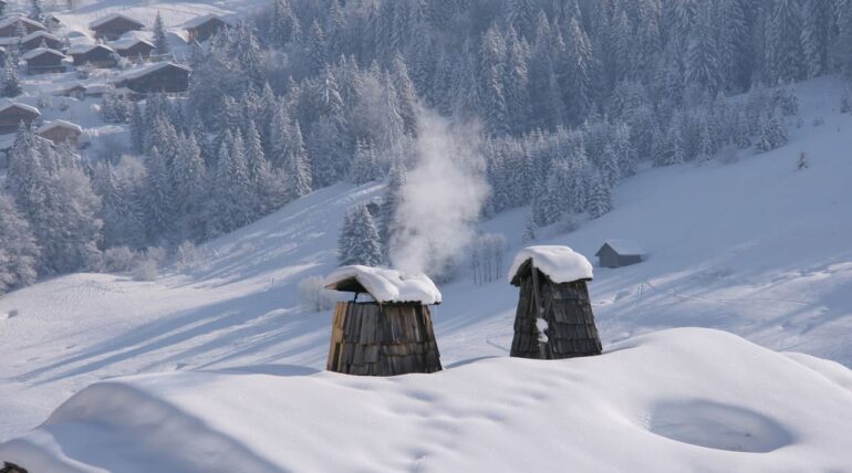 eingeheizter rauchfang mit raufangdach voll mit schnee - winterlandschaft